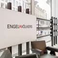 Modern real estate office interior with "ENGEL & VÖLKERS" logo on a wall, chairs, large window, and street view outside.