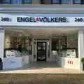 Street view of Engel & Völkers real estate office with glass doors, window displays, holiday decorations, and black framed windows.