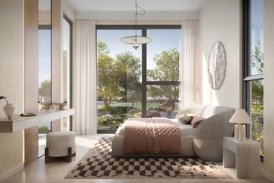Modernes Schlafzimmer mit großen Fenstern, einem gemütlichen Bett mit rosa Akzenten, einem karierten Teppich und einem Schminktisch. Bäume und Garten sind draußen sichtbar.