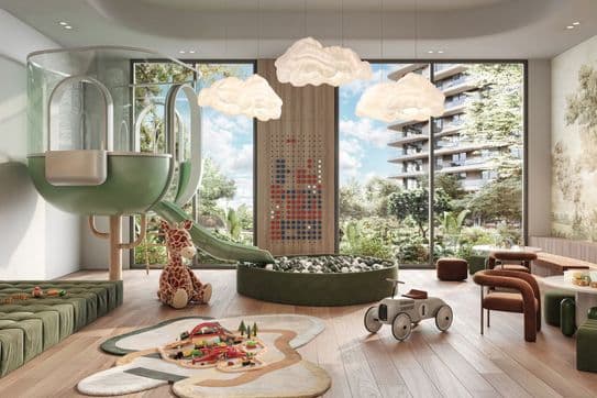 Children's playroom with a slide, ball pit, toy giraffe, and cloud-shaped lights. Large windows reveal a view of trees and a building outside.