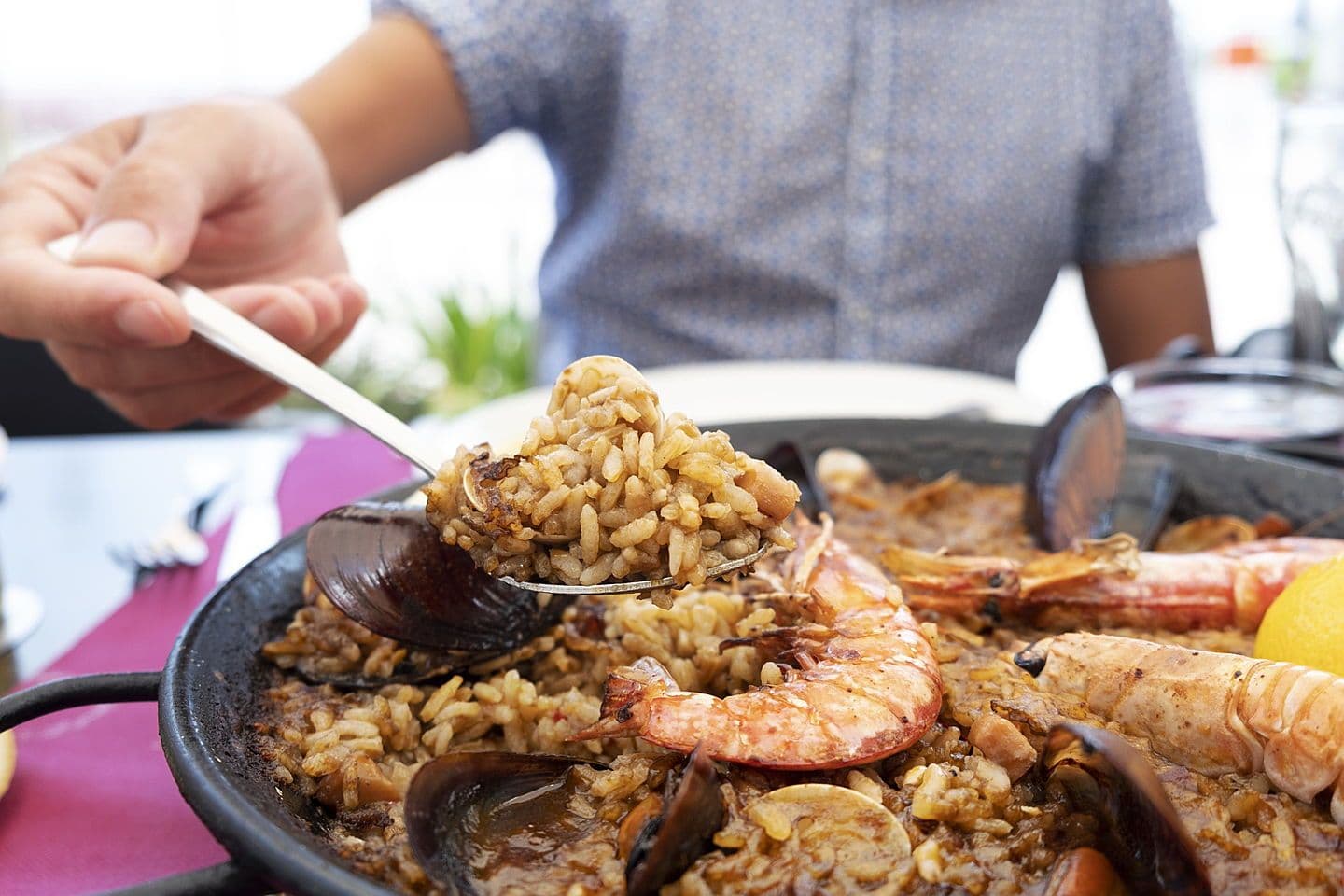 Se ve un hombre comiendo una paealla tipica con mariscos