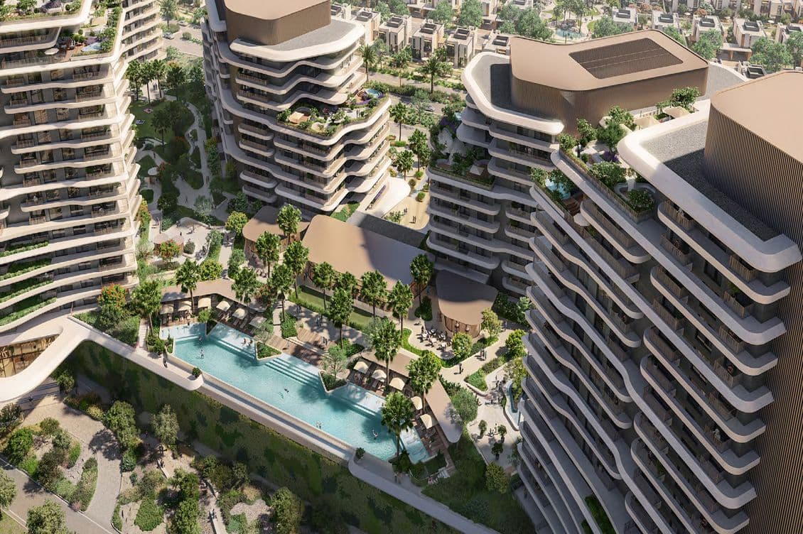 Aerial view of modern high-rise buildings with curved balconies, surrounding a central pool area and lush greenery.