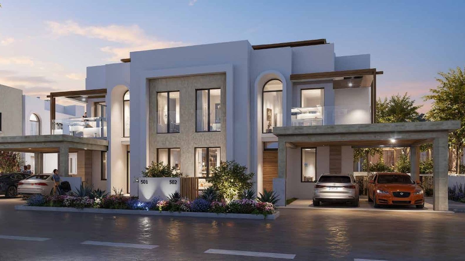 Evening view of a Hayat Residences townhouse with cars parked in front, residents on balconies, and warm interior lights highlighting the modern design.