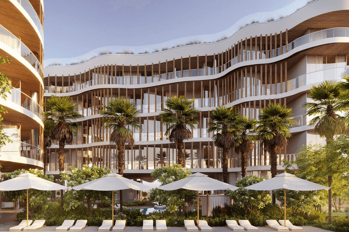 Modern building with wavy balconies, palm trees, and poolside loungers under umbrellas, set in a sunny, landscaped area.
