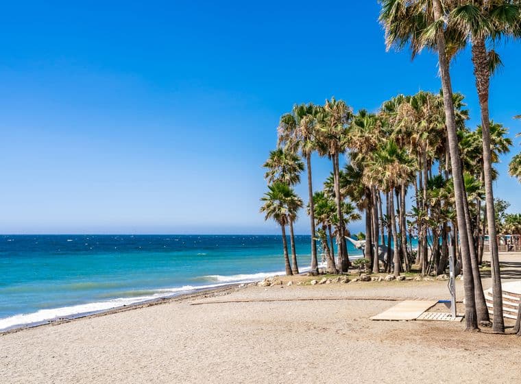 Marbella Weststrand mit feinem Sand, kristallklarem Meer und vielen paradiesischen Palmen.