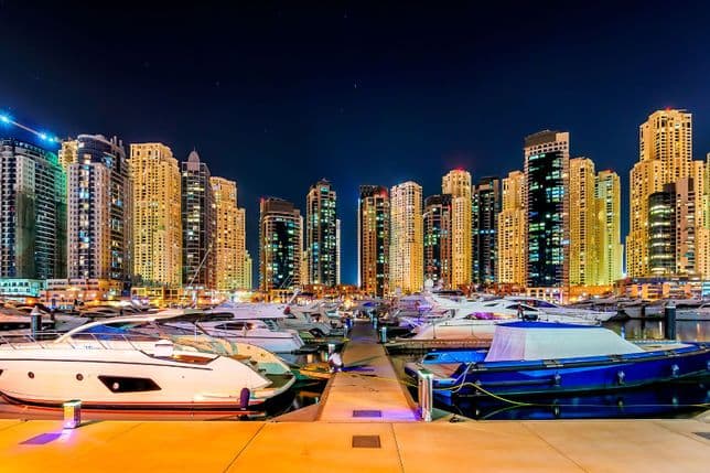 Luxury yachts and apartment buildings in Dubai Marina at night