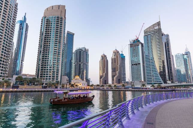 A traditional boat cruising through Dubai Marina at sunset