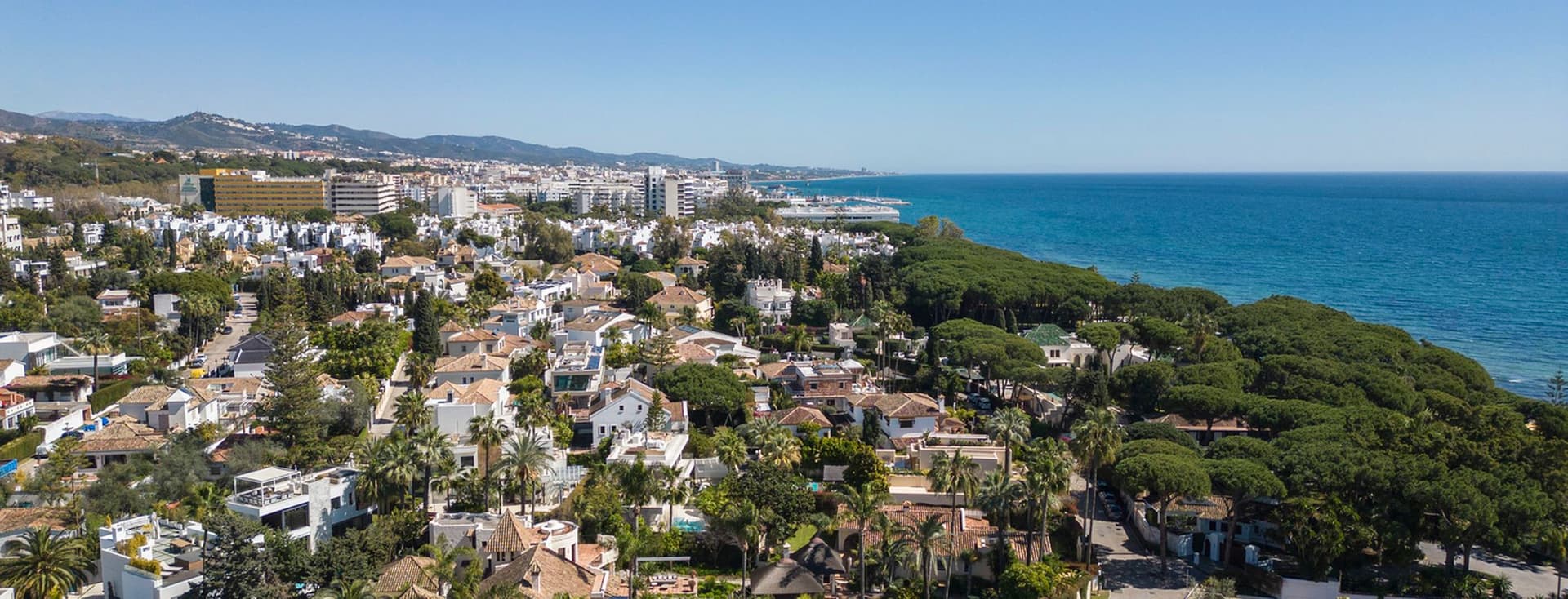 Aerial view of the Golden Mile showing villas and flats surrounded by green plants next to the blue sea