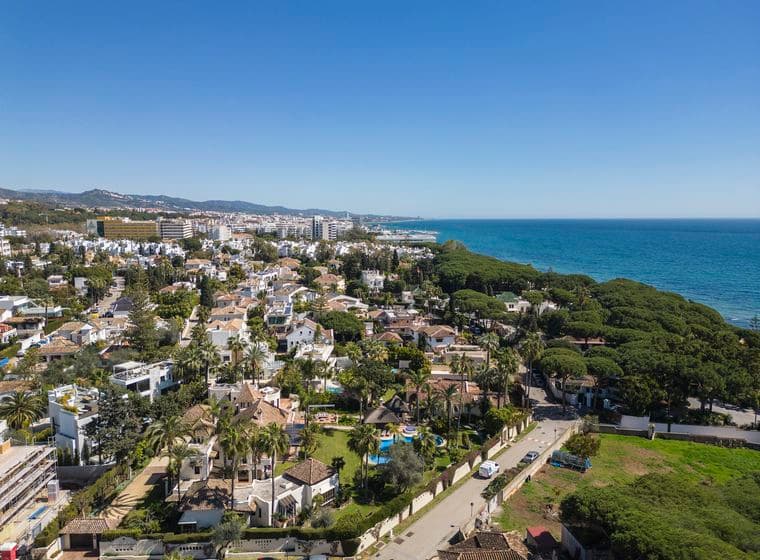 Luftaufnahme der Golden Mile, die Villen und Wohnungen zeigt, umgeben von grünen Pflanzen neben dem blauen Meer.