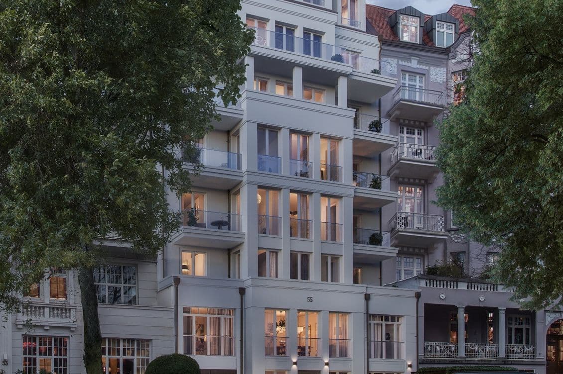 Modernes mehrstöckiges Wohnhaus mit Balkonen, eingerahmt von Bäumen und einem geparkten Auto davor, vor einem bewölkten Abendhimmel.