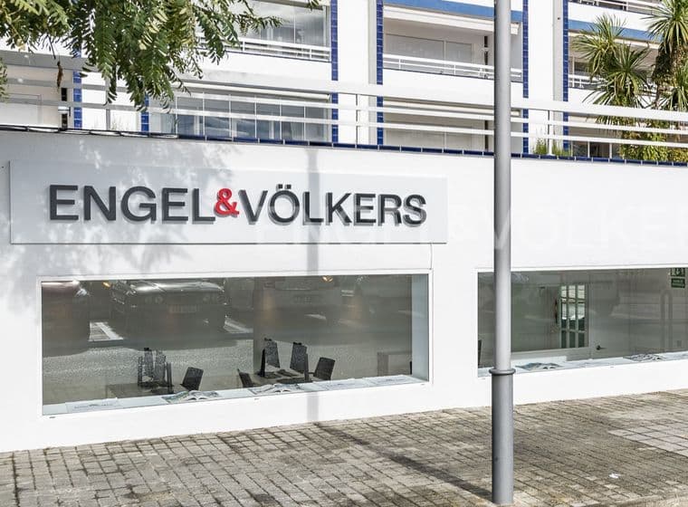 Oficina immobiliària Engel & Völkers amb una façana blanca i grans finestrals que mostren propietats.