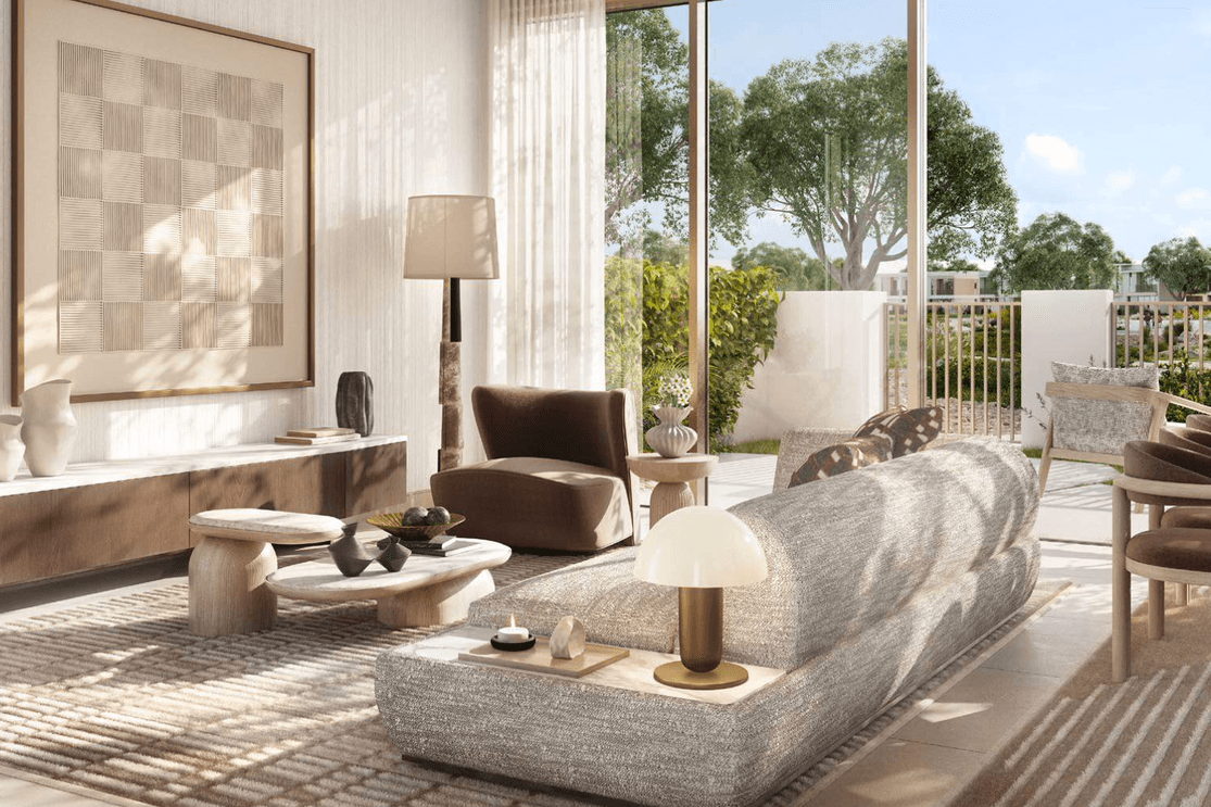 Eine helle Lounge in Vindera at The Valley mit raumhohen Fenstern und Blick auf gestaltete Gaerten sowie gruene Gemeinschaftsbereiche.