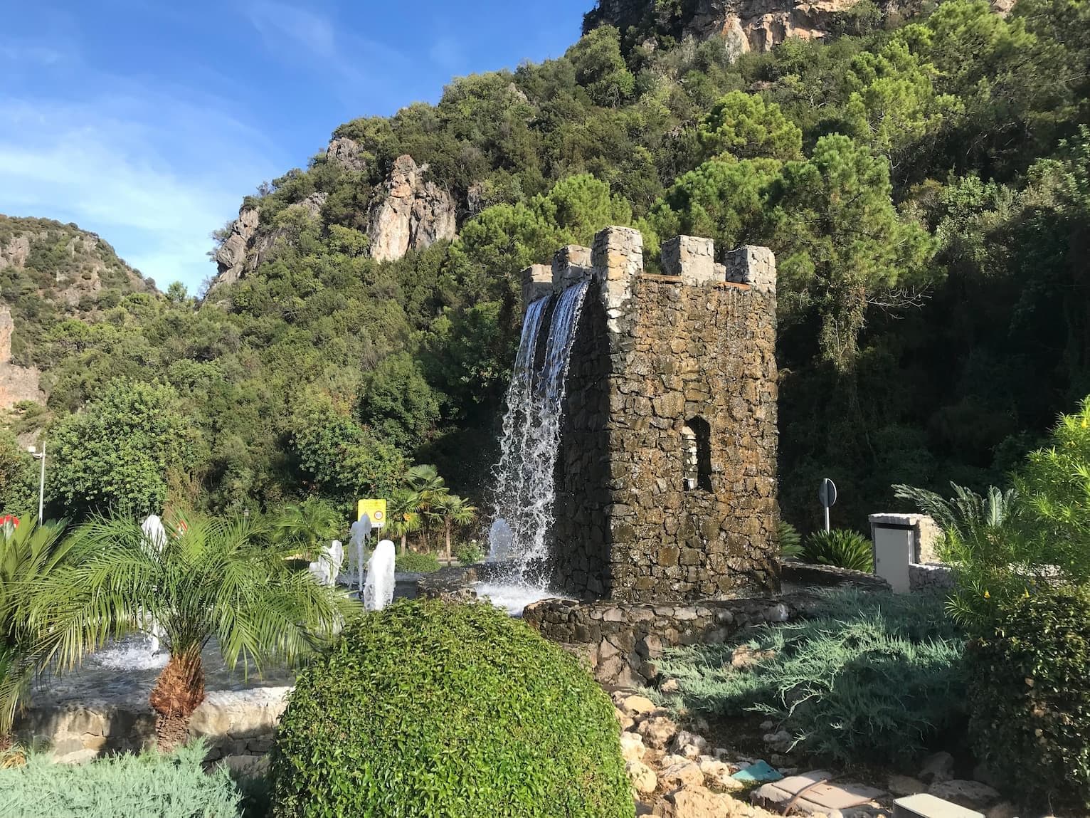 Fountain made of stone bricks in Benahavis town andalucia spain. Water runs down the walls of the tower and the rim of the tower are splashing water springs.