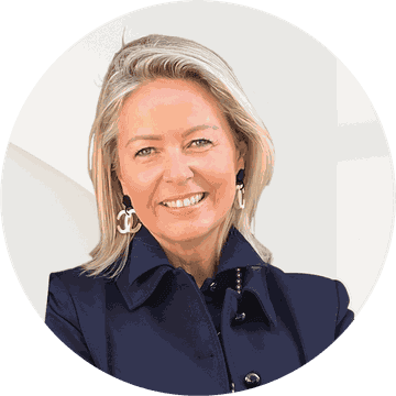 Portrait d'une femme blonde souriante portant un blazer bleu marine et des boucles d'oreilles dorées.