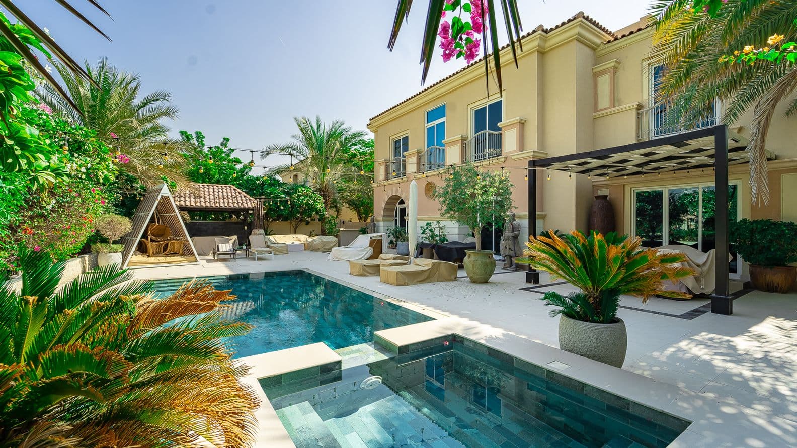 A Mediterranean-style villa in Victory Heights with a landscaped garden, shaded pergola, outdoor seating, and a modern swimming pool surrounded by lush greenery.