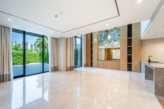 Geräumiges, modernes Wohnzimmer mit großen Fenstern, Marmorboden, zeitgenössischer Beleuchtung und Blick auf einen üppigen Garten.