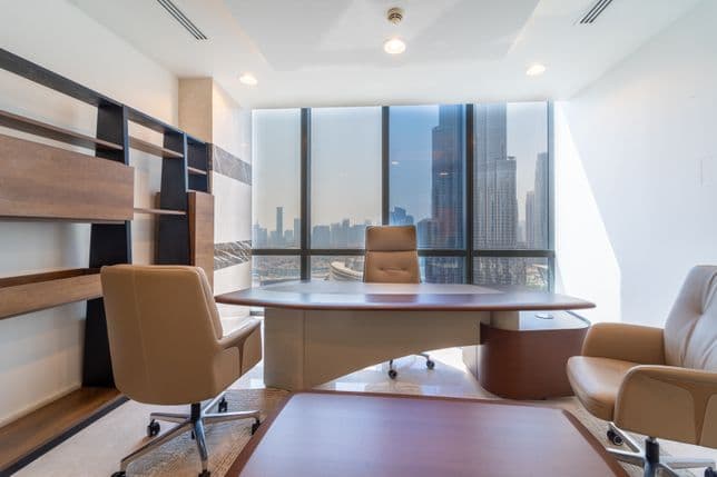 Executive meeting room in Boulevard Plaza with leather chairs around a wooden table, wall-mounted screen, and panoramic city views through large windows.