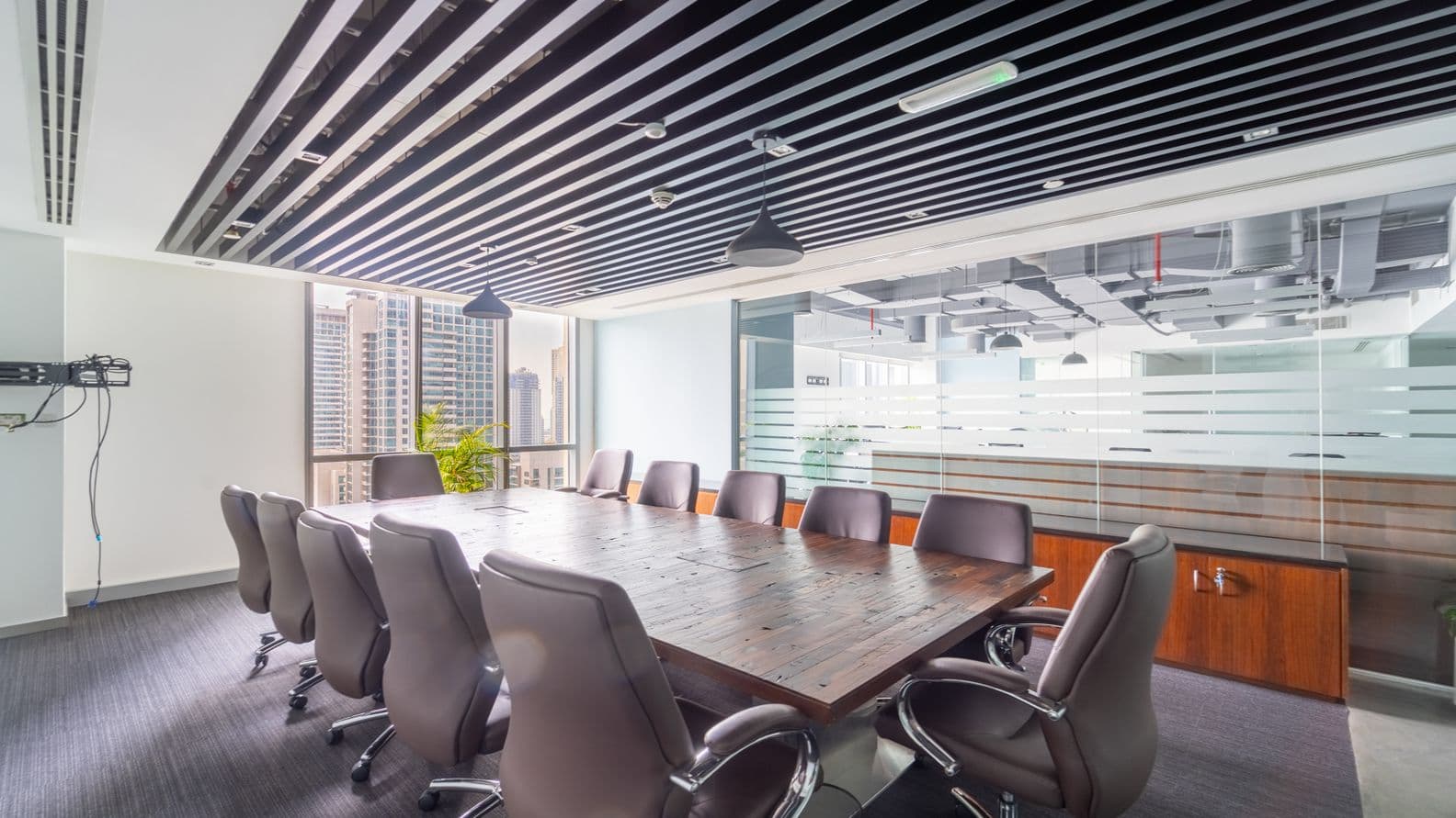 Modern office space divided by wooden frames and frosted glass panels, furnished with wooden desks and large windows providing natural light and views of Dubai’s business district.