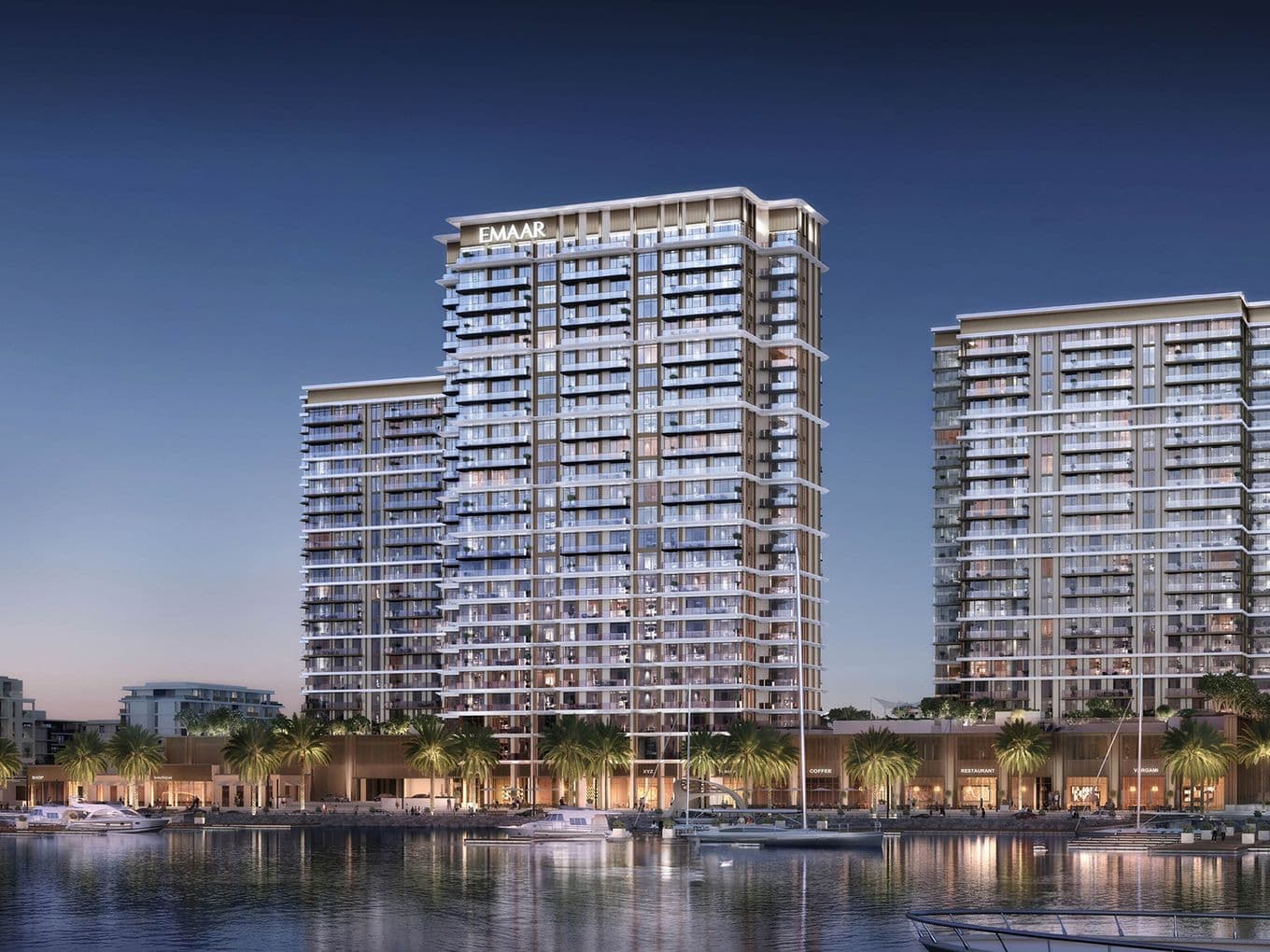 Modern waterfront high-rise buildings with illuminated windows at dusk, surrounded by palm trees and reflecting in calm water.