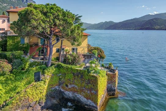 Drohnenaufnahme einer Villa am Ufer des Comer Sees, umgeben von Wasser
