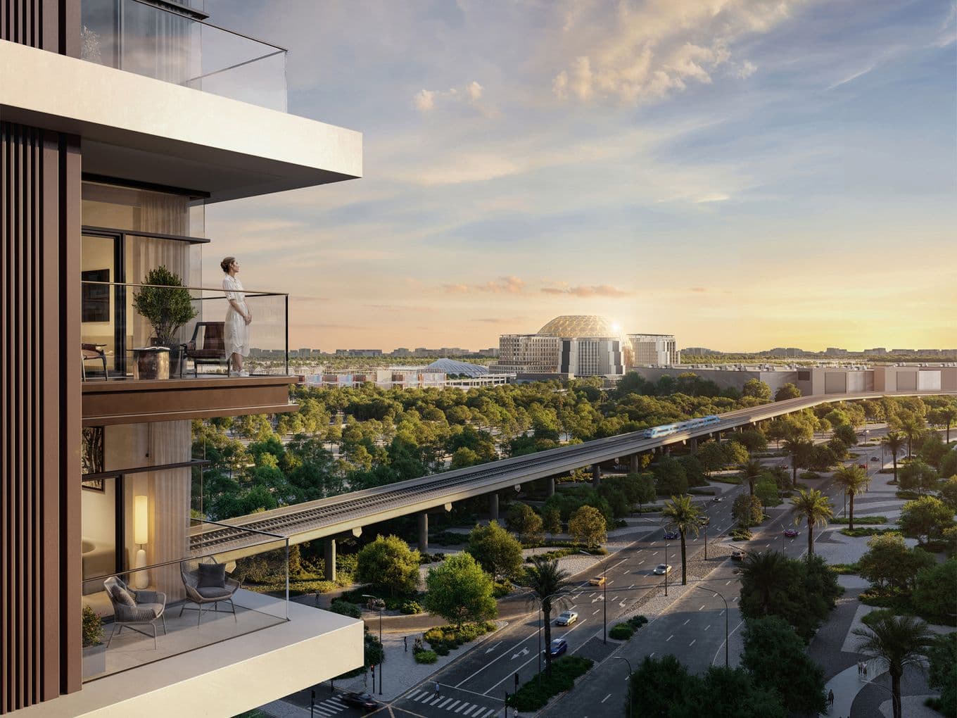 Person standing on a balcony overlooking a cityscape with modern buildings, lush greenery, and a train track under a sunset sky.