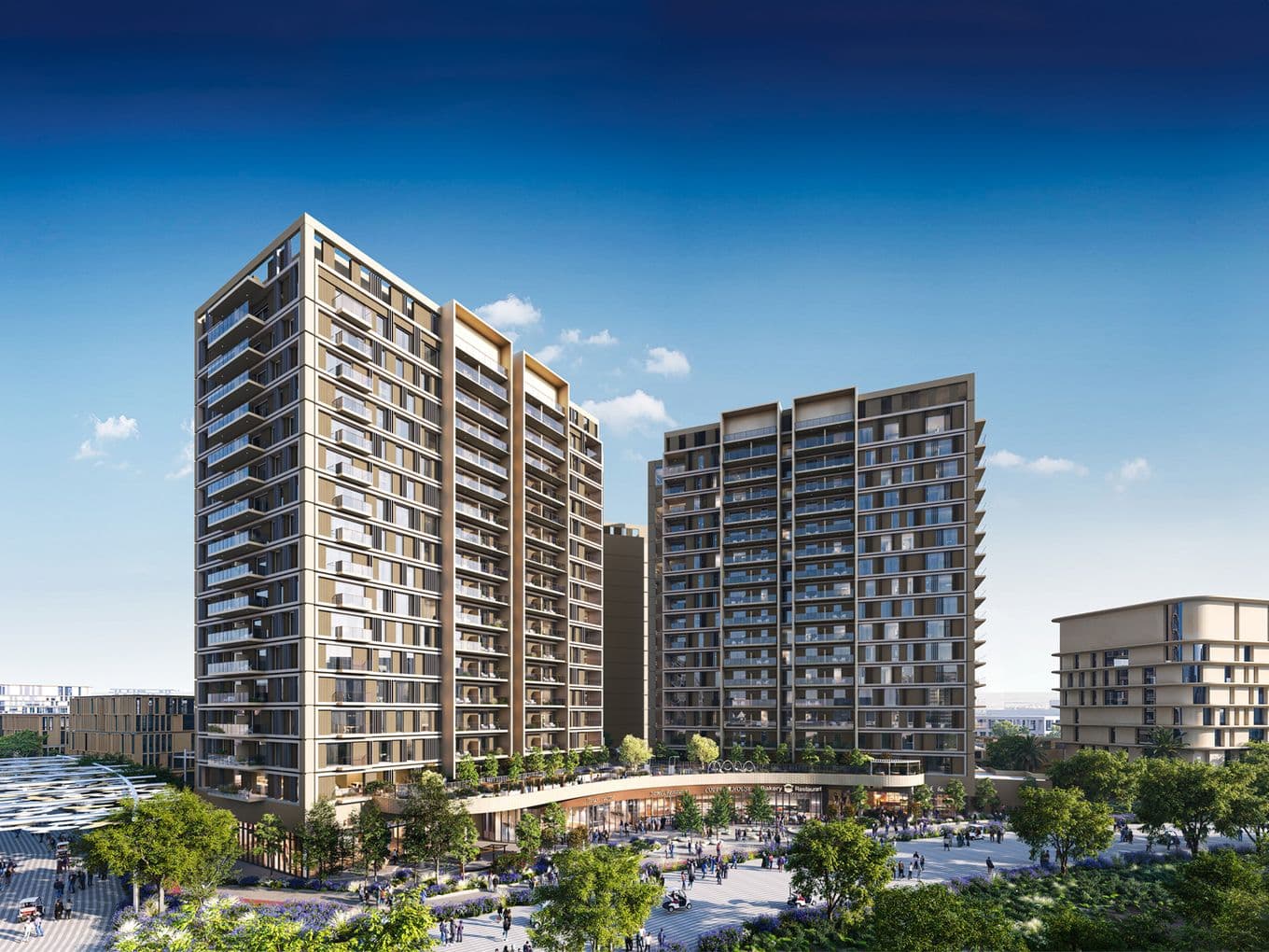 Modern high-rise apartment buildings with large windows and balconies, surrounded by trees and a plaza under a clear blue sky.