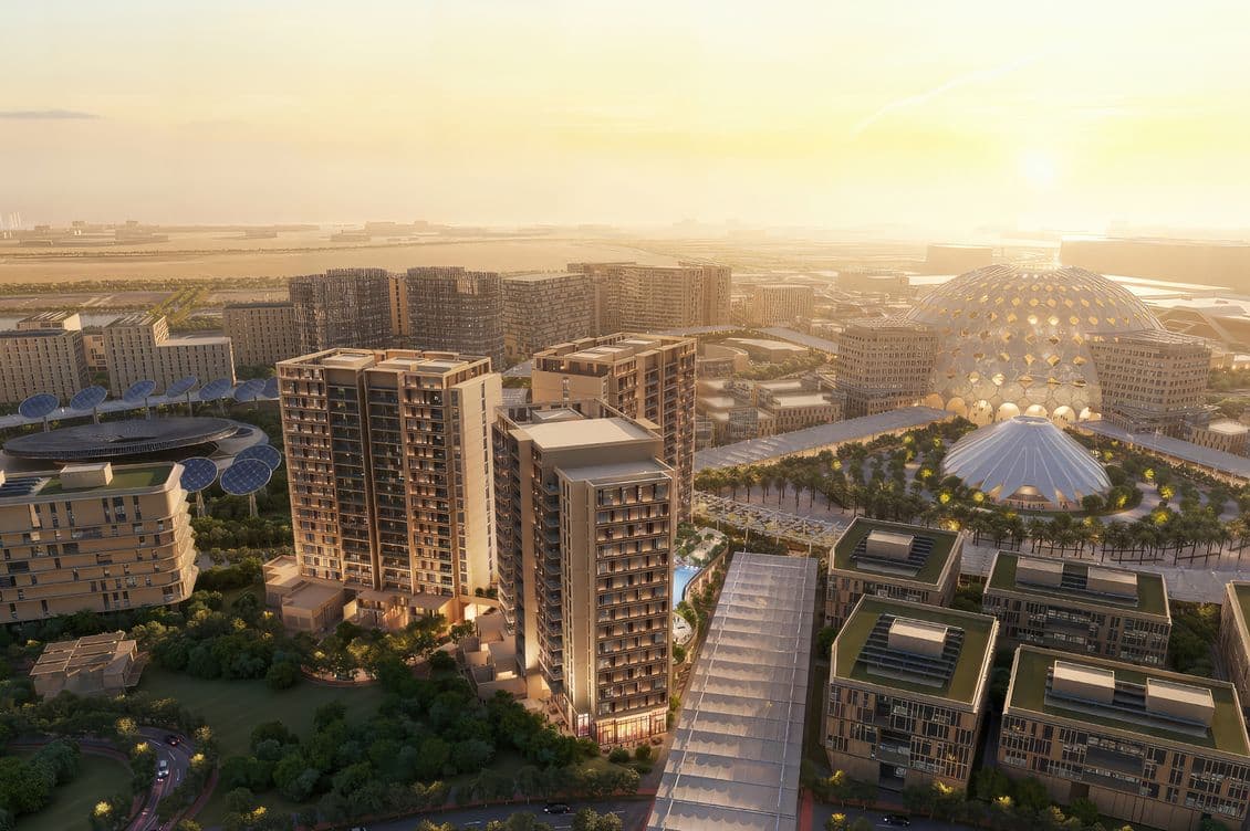 Aerial view of a modern urban landscape at sunset, featuring tall buildings, a geodesic dome, and lush greenery.