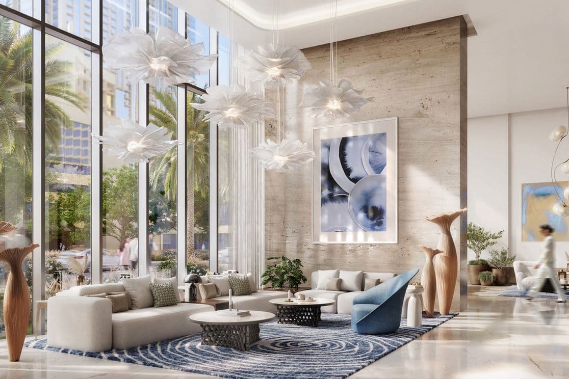 Luxurious hotel lobby with modern furniture, artistic lighting, large windows, and palm trees outside. Elegant decor and abstract art adorn the space.