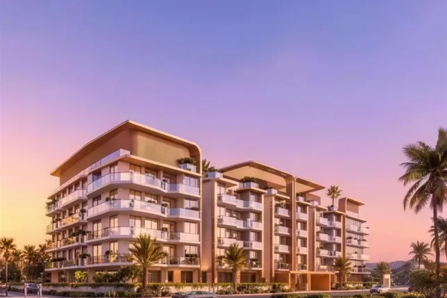 Modern residential complex with curved balconies and glass railings, palm trees, under a pastel sunset sky.
