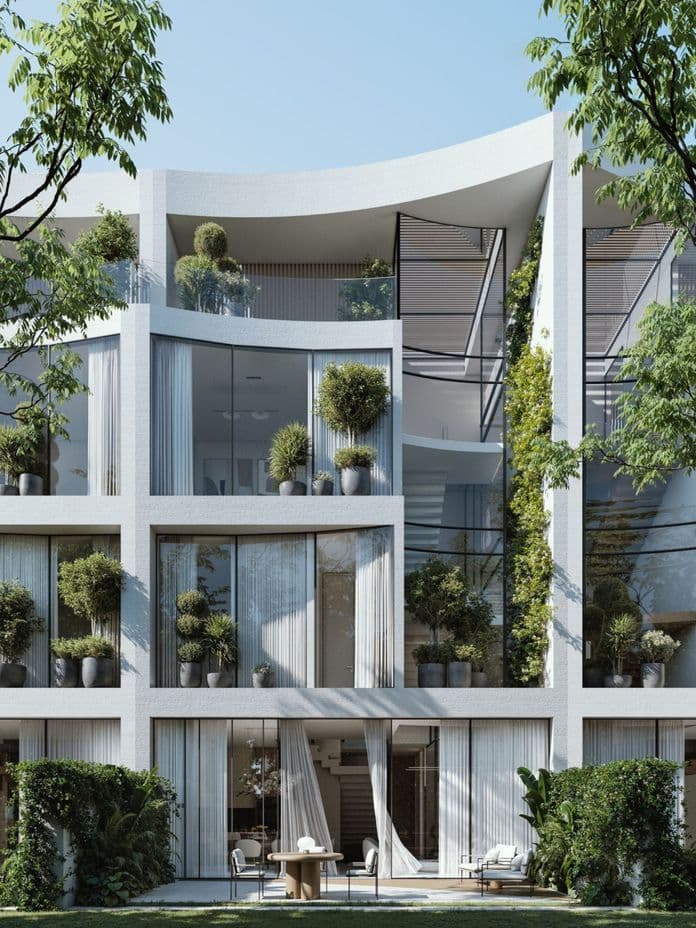 Modern white building with large windows, balconies adorned with potted plants, and greenery climbing the facade, surrounded by trees.