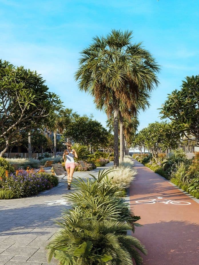 Lush landscaped walking and cycling path lined with palm trees, flowering shrubs, and benches, showcasing the outdoor lifestyle amenities in Pinewood Village.