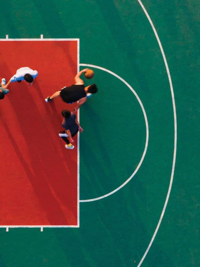 Aerial view of people playing basketball on a vibrant red and green court, showcasing active lifestyle and recreational amenities at Binghatti Circle.