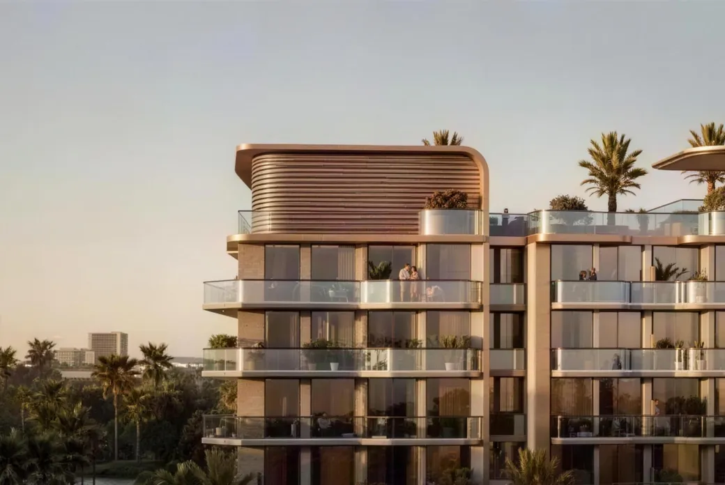 Modern glass apartment building with a rounded top, spacious balconies, and palm trees at sunset.