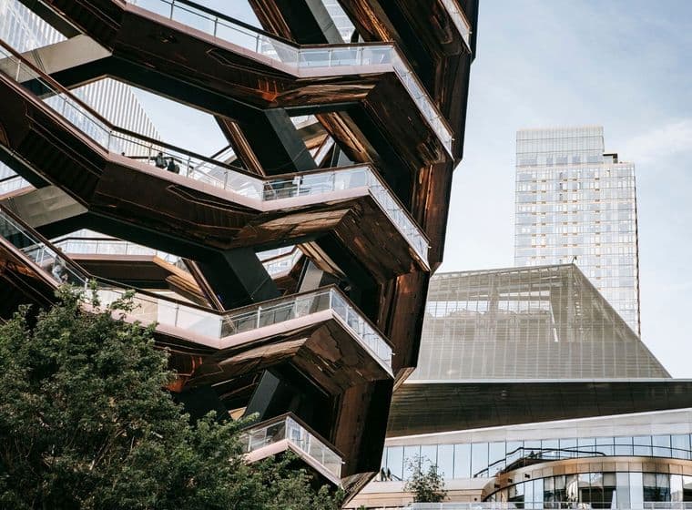 Außenansicht des Vessel, einer kupferfarbenen wabenförmigen Struktur mit Treppen und Glasgeländern, vor dem Hintergrund moderner Gebäude.