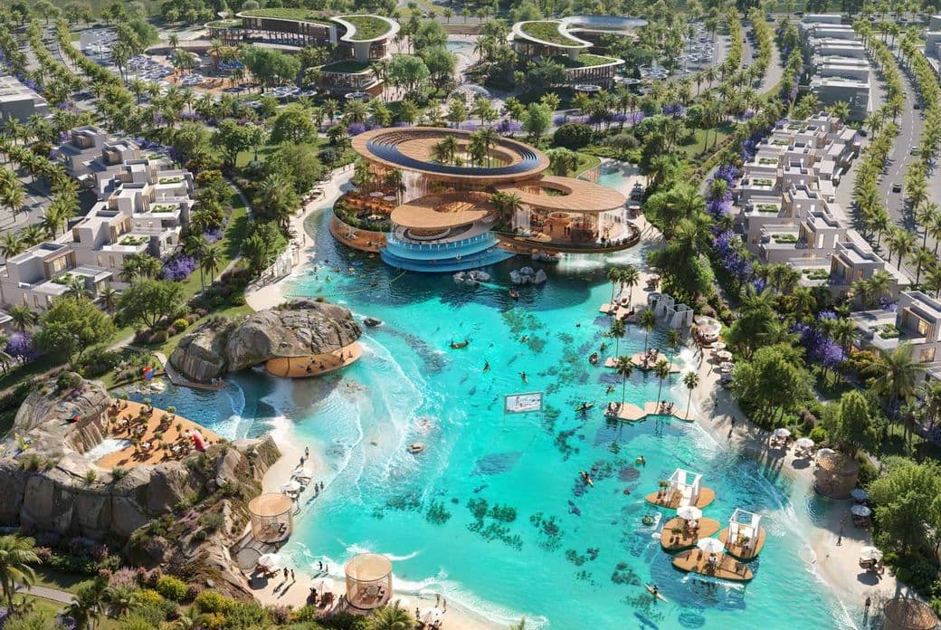 Aerial view of a luxurious resort with turquoise lagoon, sandy beaches, modern architecture, and surrounding greenery and palm trees.