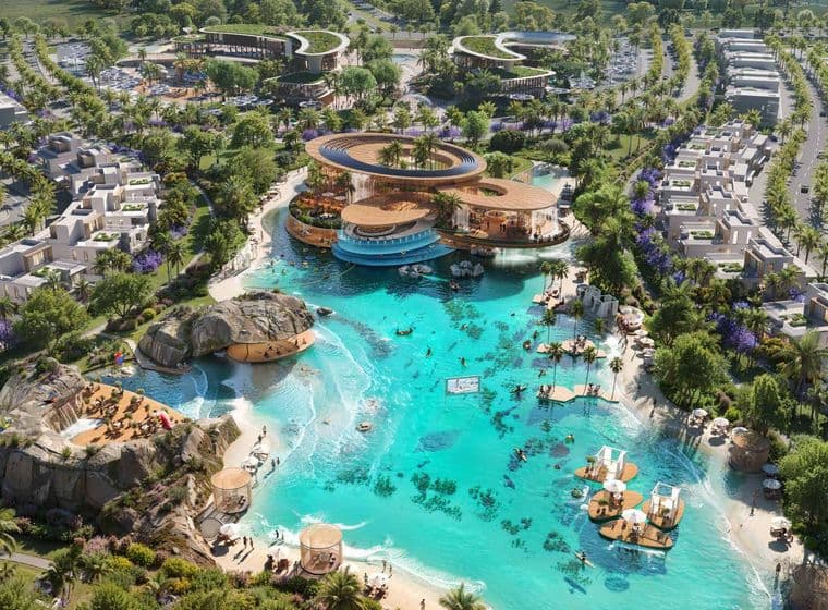Aerial view of a luxurious resort with turquoise lagoon, sandy beaches, modern architecture, and surrounding greenery and palm trees.