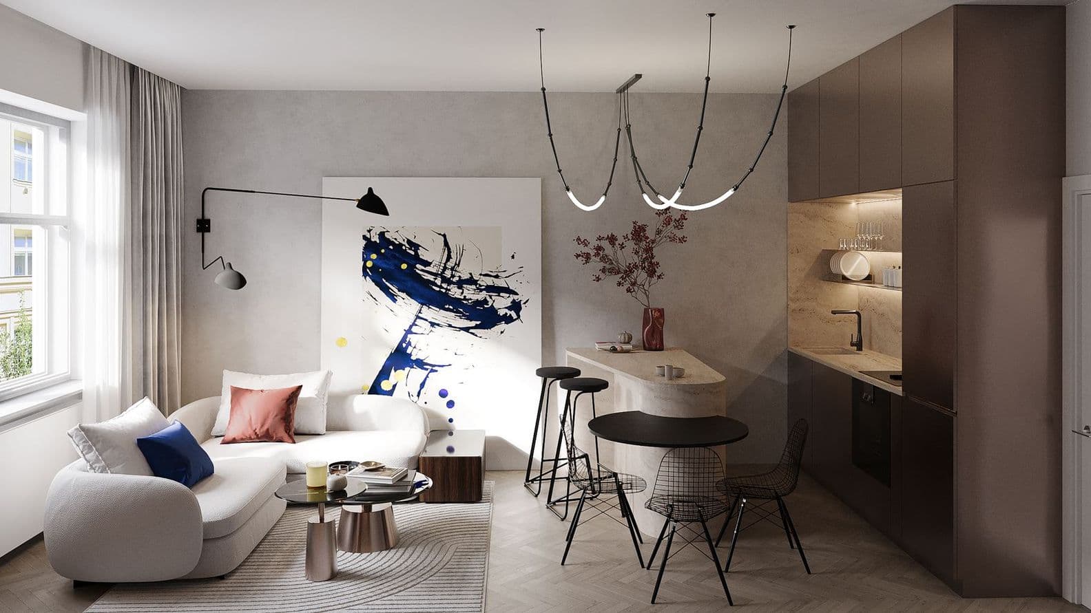 Modern living room with a white curved sofa and cushions in soft tones. A large black-and-white abstract painting hangs on the wall. On the right, the kitchen features brown cabinets and a stone countertop that extends into a bar area with three stools. A round dining table with wire-frame chairs stands in front of the bar. A striking designer light fixture hangs from the ceiling.