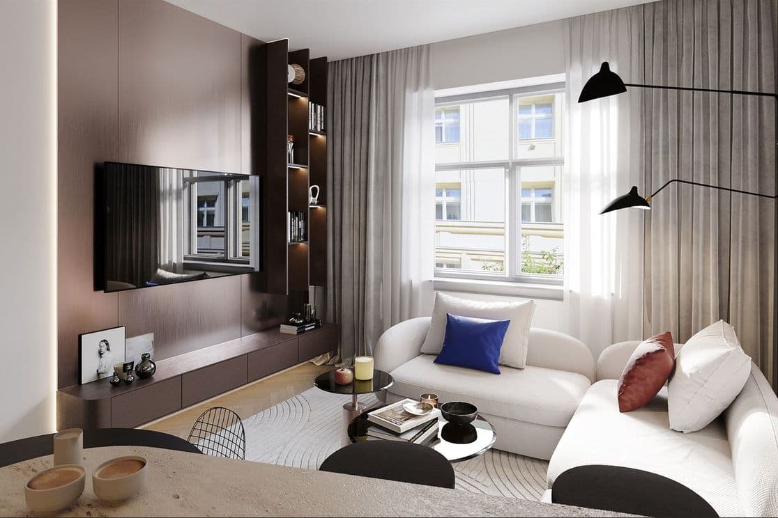 Interior of a living room featuring a large window, a white curved sofa with colorful cushions, a black wall-mounted lamp, and round coffee tables. Opposite the sofa is a mounted TV and a dark built-in bookshelf. Part of a dining table appears in the foreground.