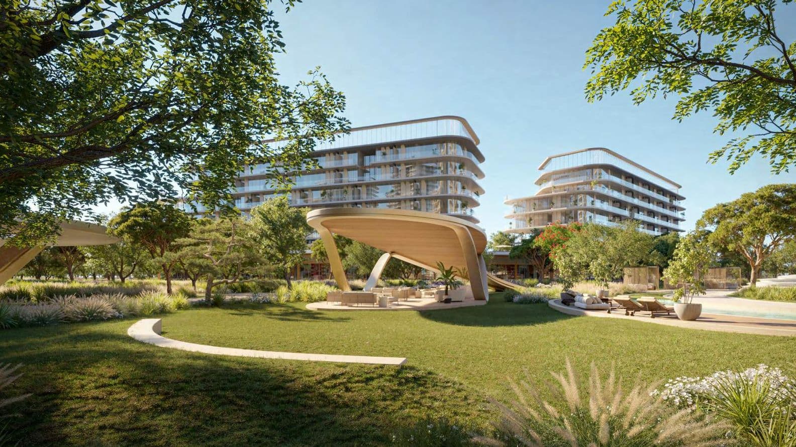 Modern buildings with curved designs in a lush, landscaped park featuring grassy areas, trees, and walkways under a clear blue sky.