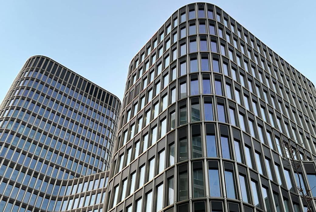Modern office buildings with glass façades and curved edges under a clear blue sky.
