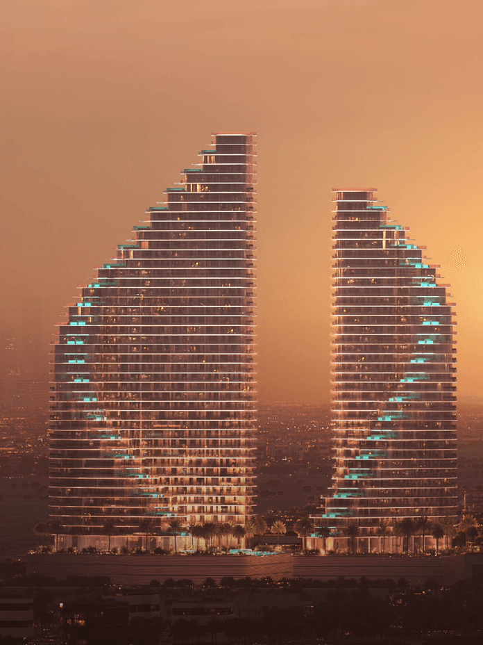 Two sail-shaped skyscrapers at sunset, with glowing lights and a hazy cityscape in the background.