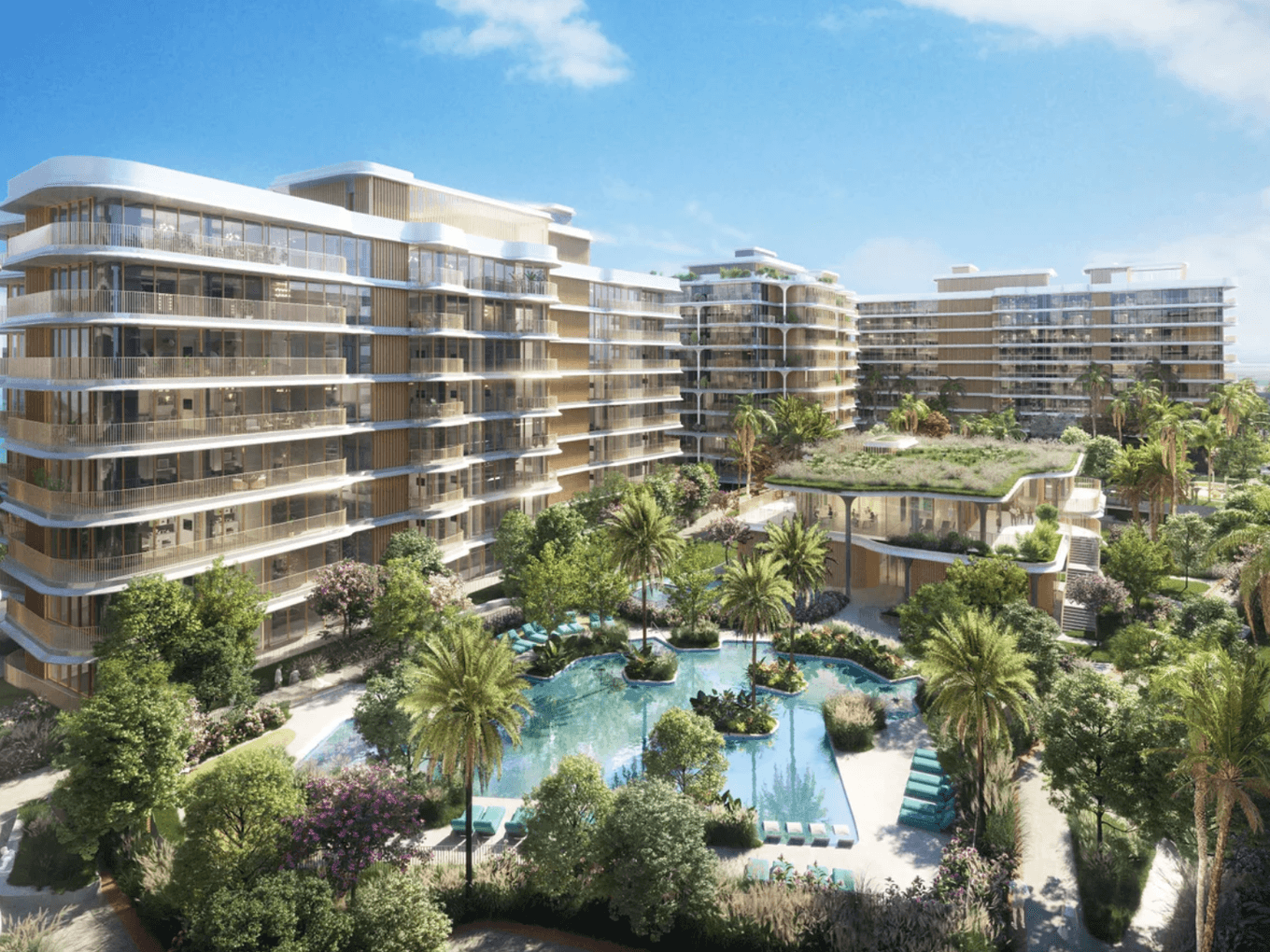 Modern apartment complex with multiple buildings, a central pool, lush greenery, and blue sky in the background.
