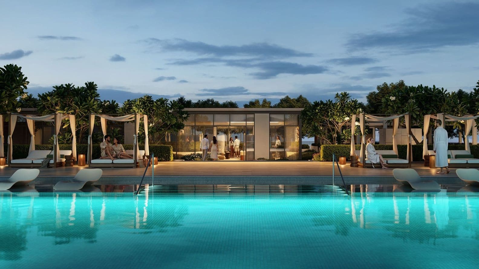 Evening view of illuminated infinity pool, cabanas, and landscaped relaxation areas.