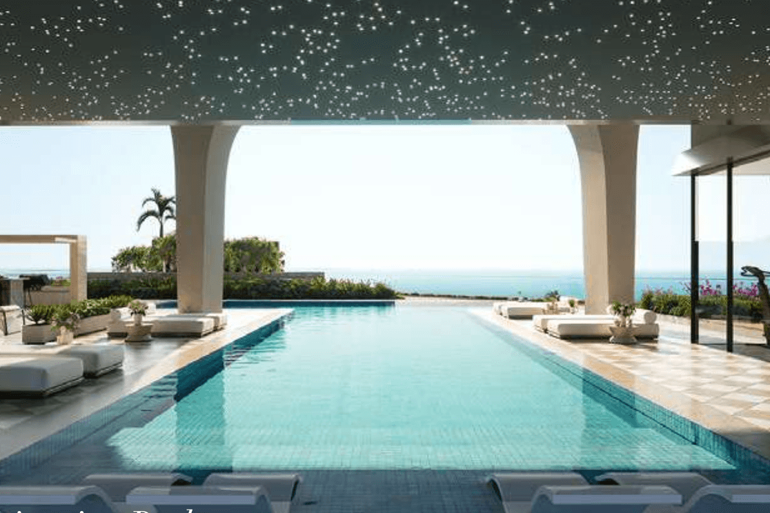 Outdoor pool at ELLE Residences with sunbeds, seating lounges and landscaped podium views.