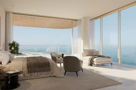 Luxuriöses Schlafzimmer mit Meerblick, Bett, Sesseln und großen Fenstern. Neutrale Töne und modernes Dekor schaffen eine ruhige Atmosphäre.