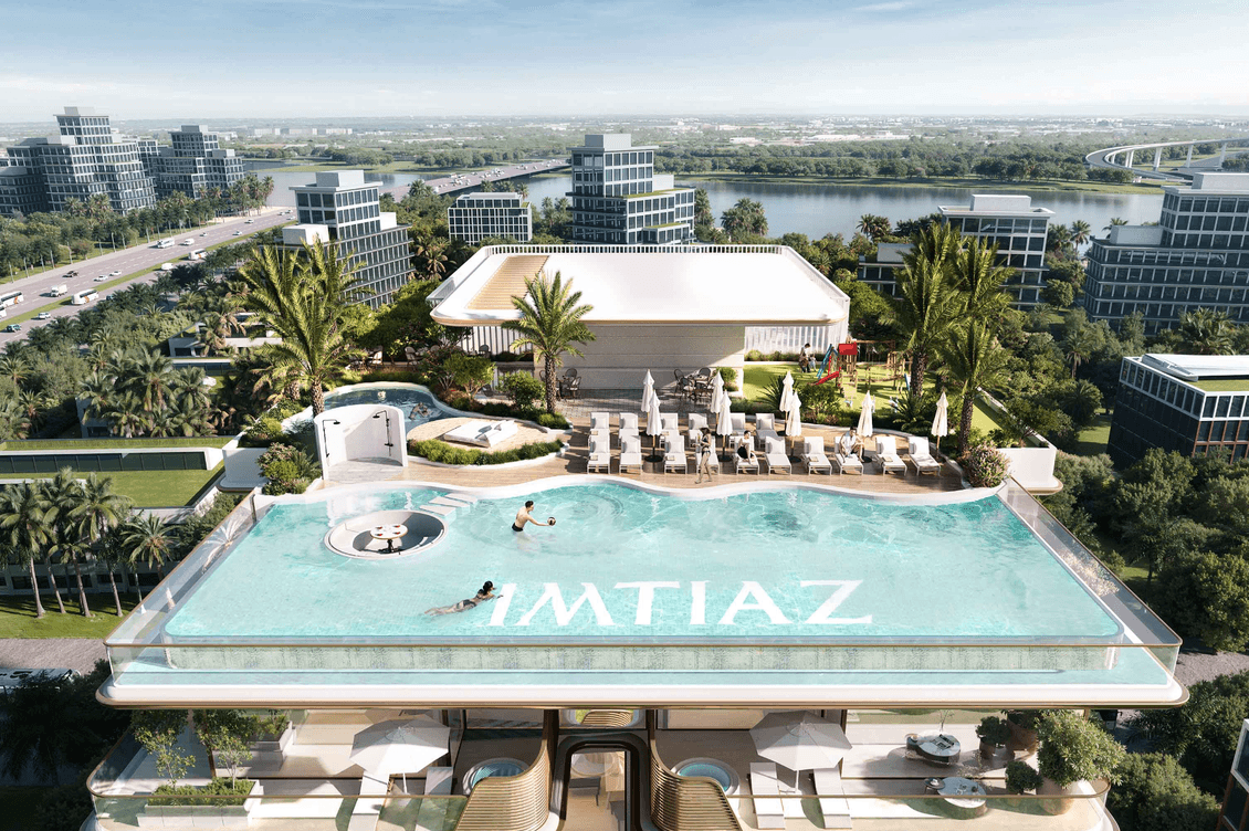Rooftop amenities at Sunset Bay 5 featuring an infinity pool, sun loungers, landscaped seating areas, and elevated views over the surrounding community.