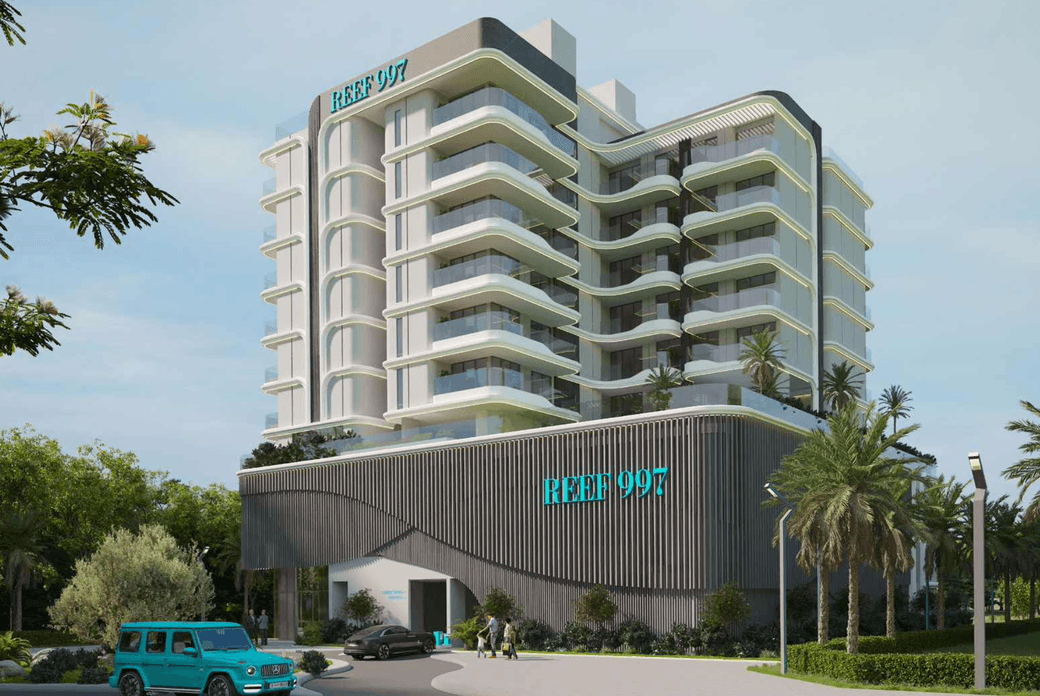 Modern multi-story building with curved balconies, labeled "REEF 997," surrounded by palm trees and greenery, with a parked blue vehicle.