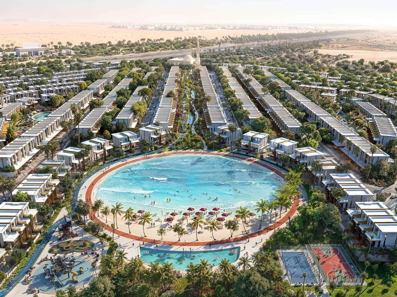 Aerial view of a luxury residential development with a large circular pool, sandy beach, palm trees, playground, and sports courts surrounded by villas.