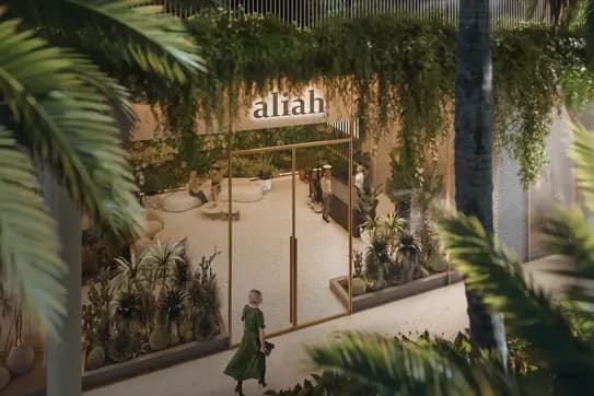 A woman in a green dress walks by a tropical-themed storefront with lush plants and the sign "afiah" above the entrance.