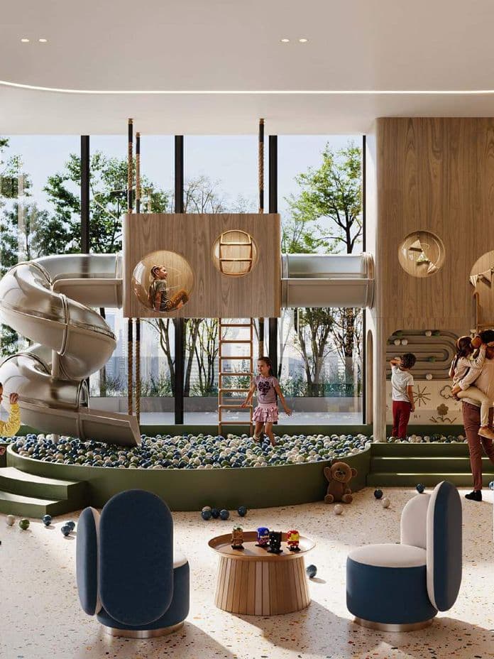 Kinder spielen in einem modernen Indoor-Spielplatz mit Rutsche, Kletterstrukturen und Sitzgelegenheiten. Große Fenster lassen natürliches Licht herein.